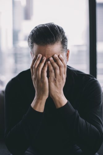 person-holds-hands-to-their-face